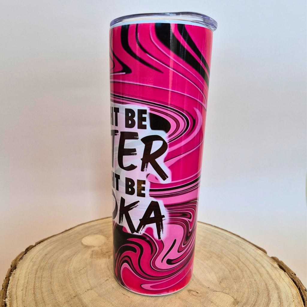 A tall, slim tumbler with a pink, black, and white marbled swirl pattern and the text 'NOT BE TER RIT BE OKA' in black, displayed on a rustic wood slice against a white background