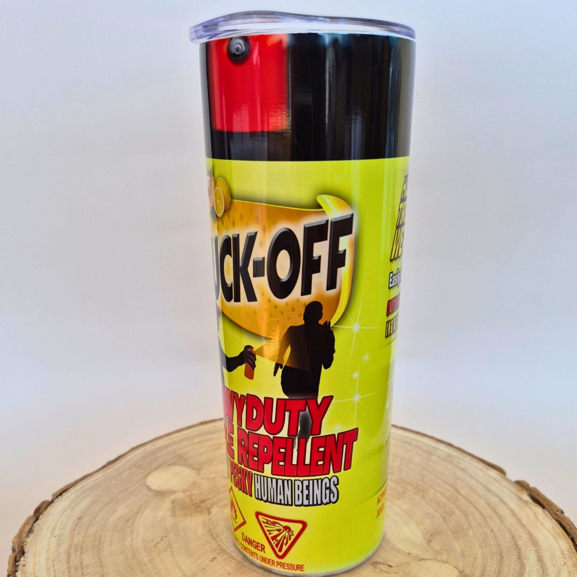 A can of 'Blind-Off' Human Beings Repellent spray, featuring a bright yellow label with black and red text, displayed on a rustic wood slice against a plain light background.