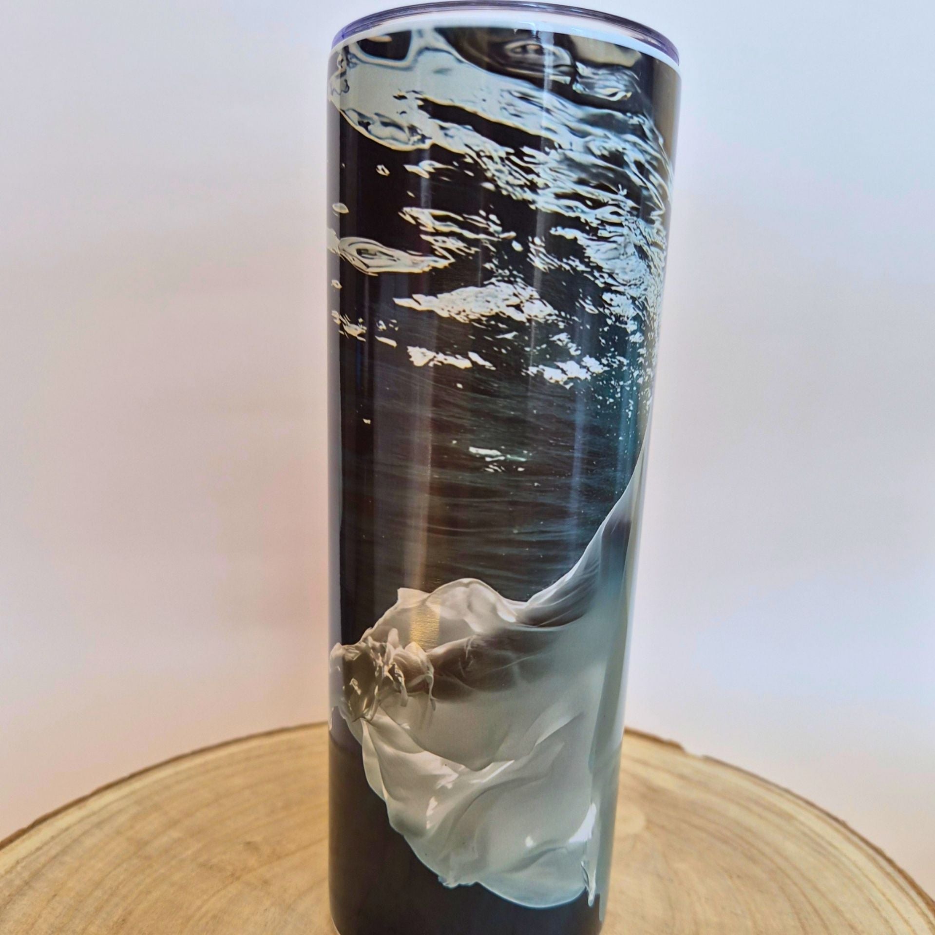 A tall, slim tumbler with a black and gray abstract watercolor design, resting on a round wooden slice against a white background with 'Memory Metal' watermarks.