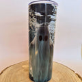 A clear cylindrical tumbler with a printed ghost design under rippling water, shown standing on a round wood slice against a plain light background.