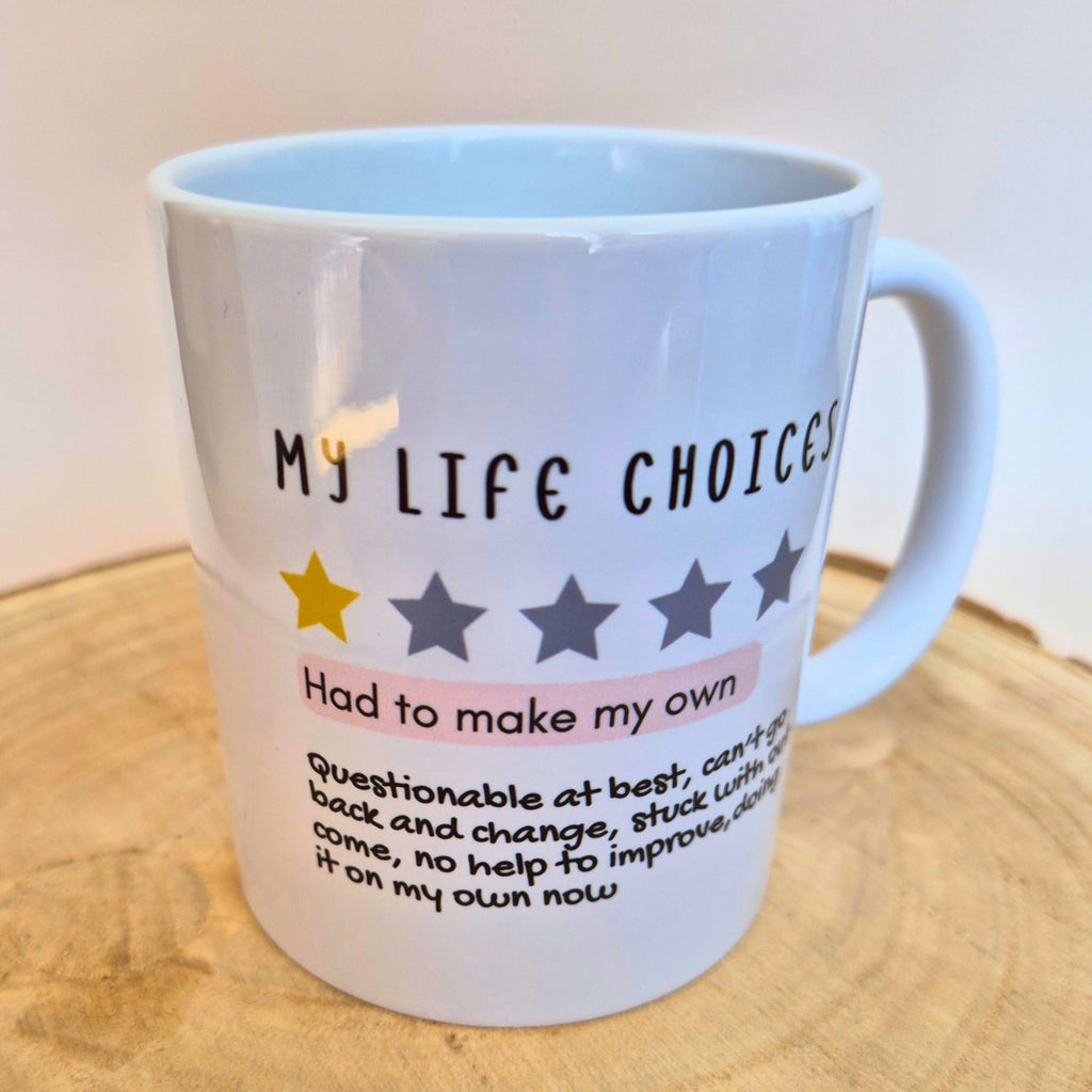 A white ceramic mug with a humorous quote about life choices and a star rating graphic, displayed on a wooden surface with a neutral background.